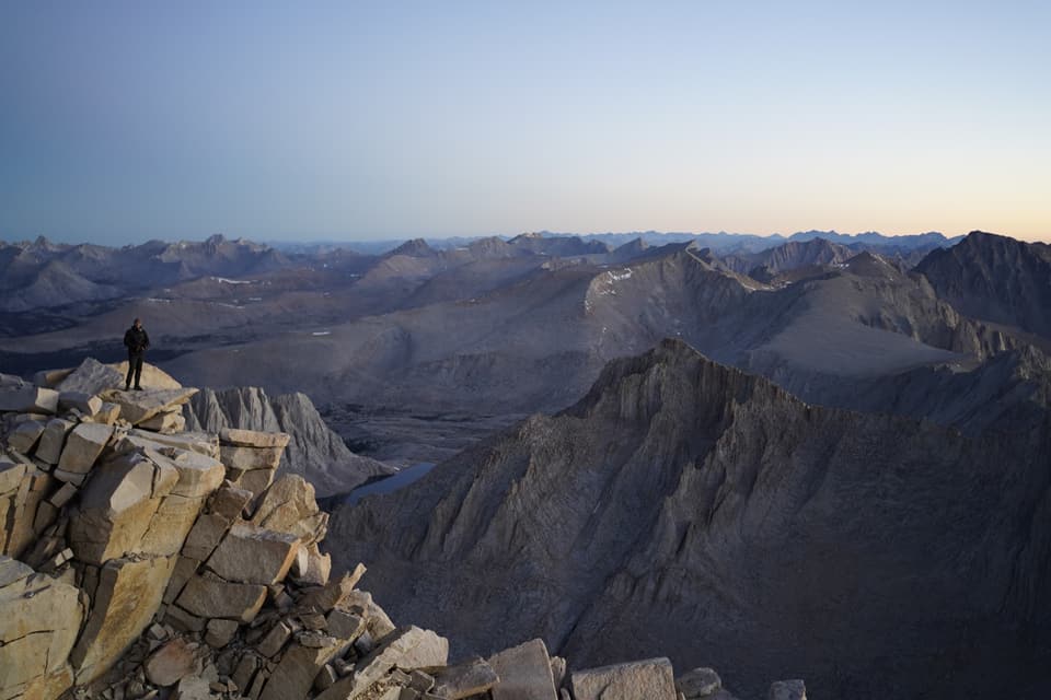 A lone figure on the Whitney summit above a sea of Sierra peaks at dusk, day 44