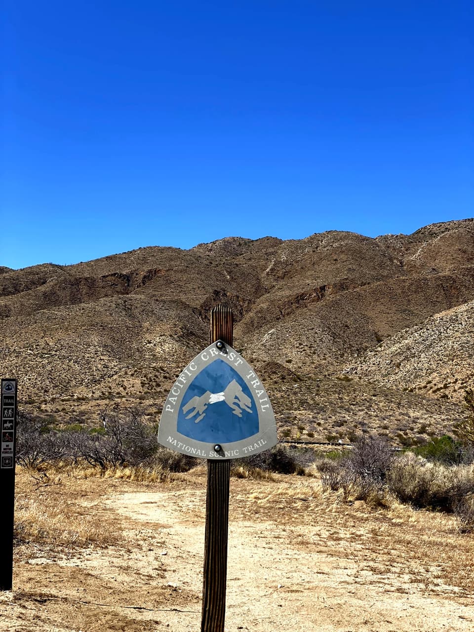 a PCT emblem on a post at the desert floor