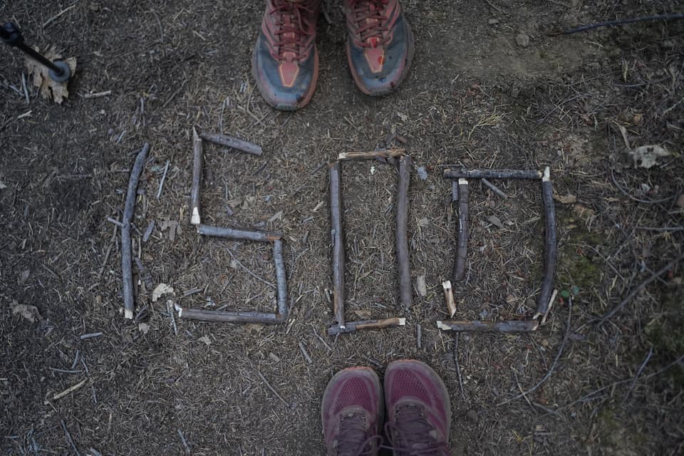 the number 1500 laid out in sticks on the trail between two pairs of trail runners