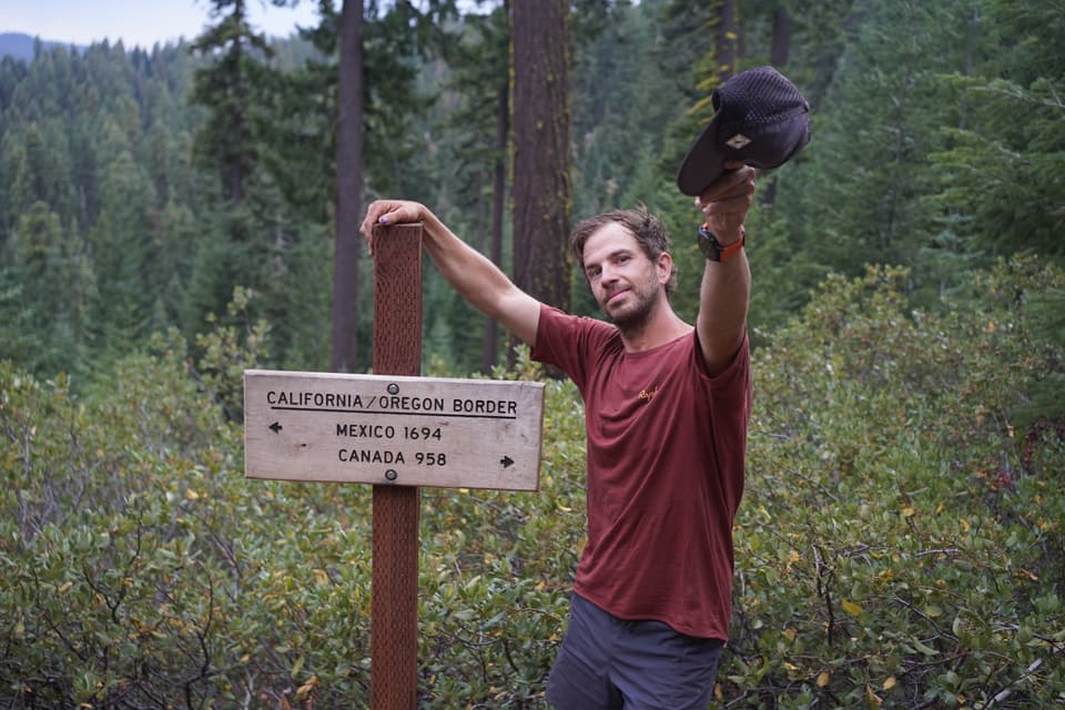 Atlas tossing his cap above the California and Oregon border sign