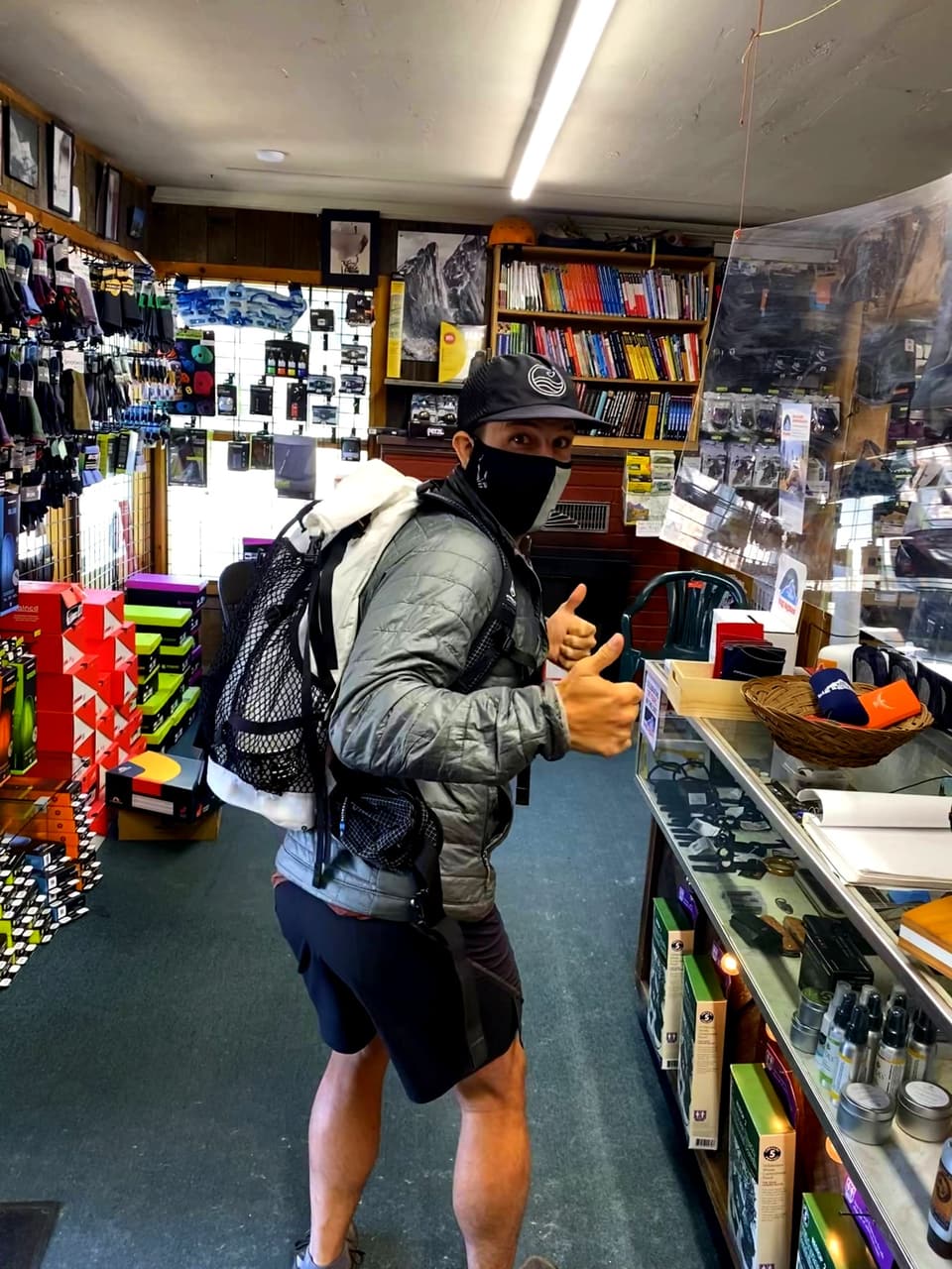 Atlas giving a thumbs up in an Idyllwild gear shop wearing a new white Hyperlite pack
