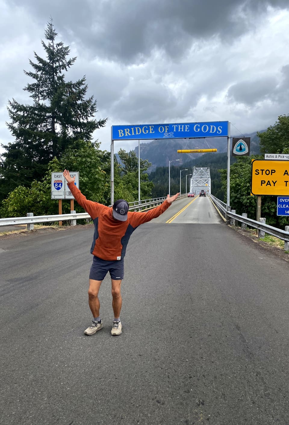 Atlas leaning back with his arms up under the Bridge of the Gods sign