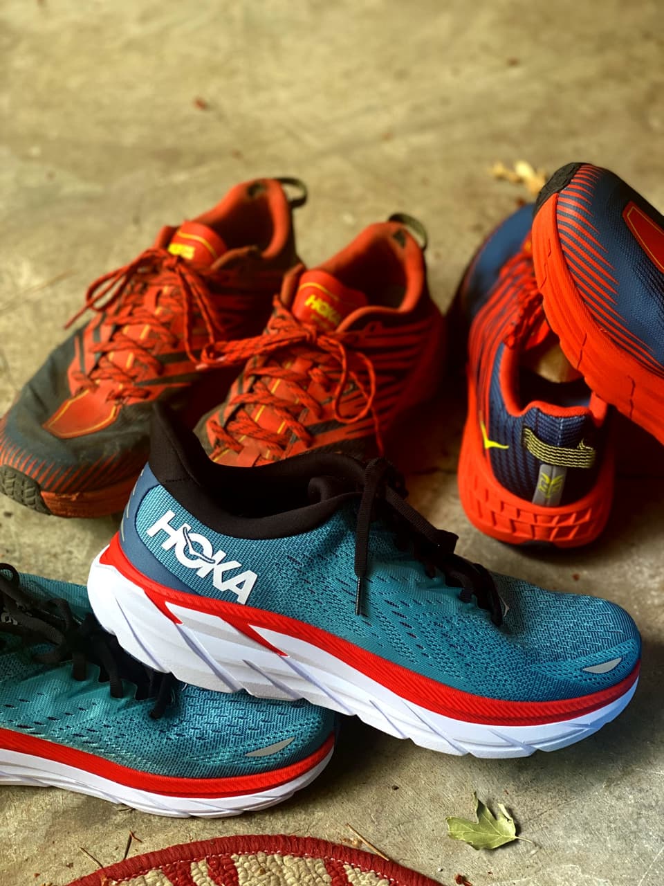 two pairs of worn Hoka trail runners on concrete