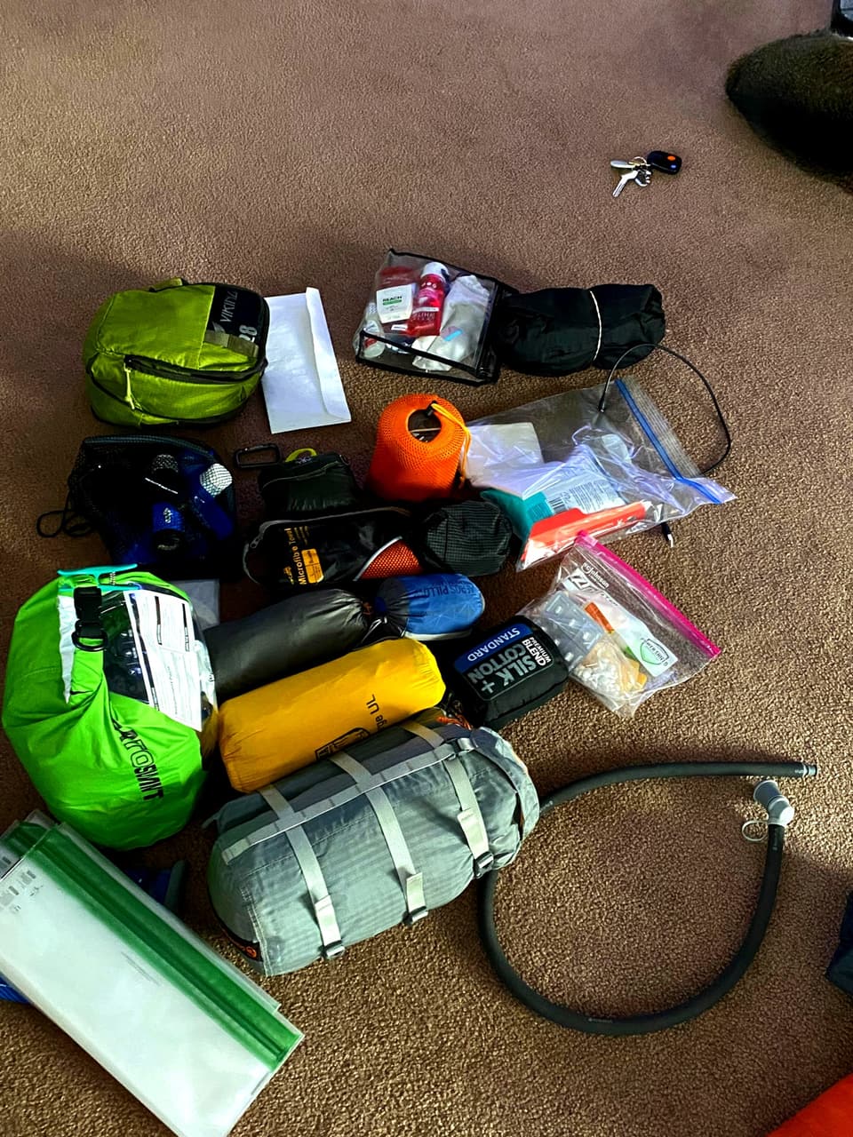 Atlas's backpacking gear laid out on a carpet before the PCT