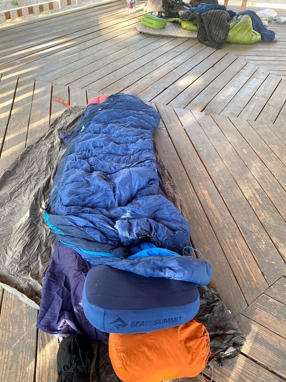 a blue Sea to Summit sleeping bag and Aeros pillow laid out on a wooden deck