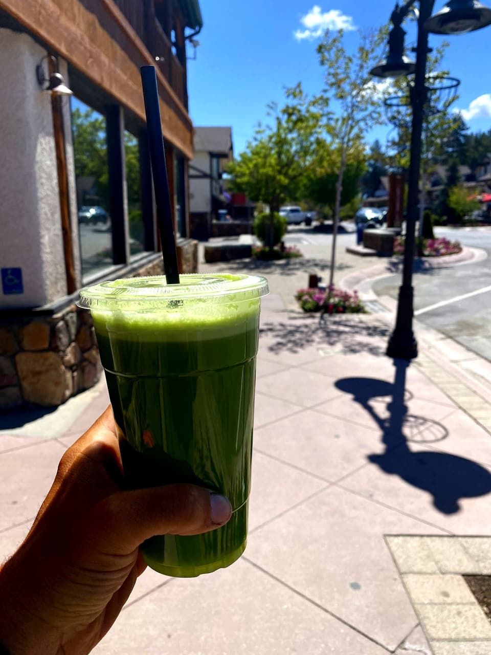 a green juice held up on a Big Bear sidewalk
