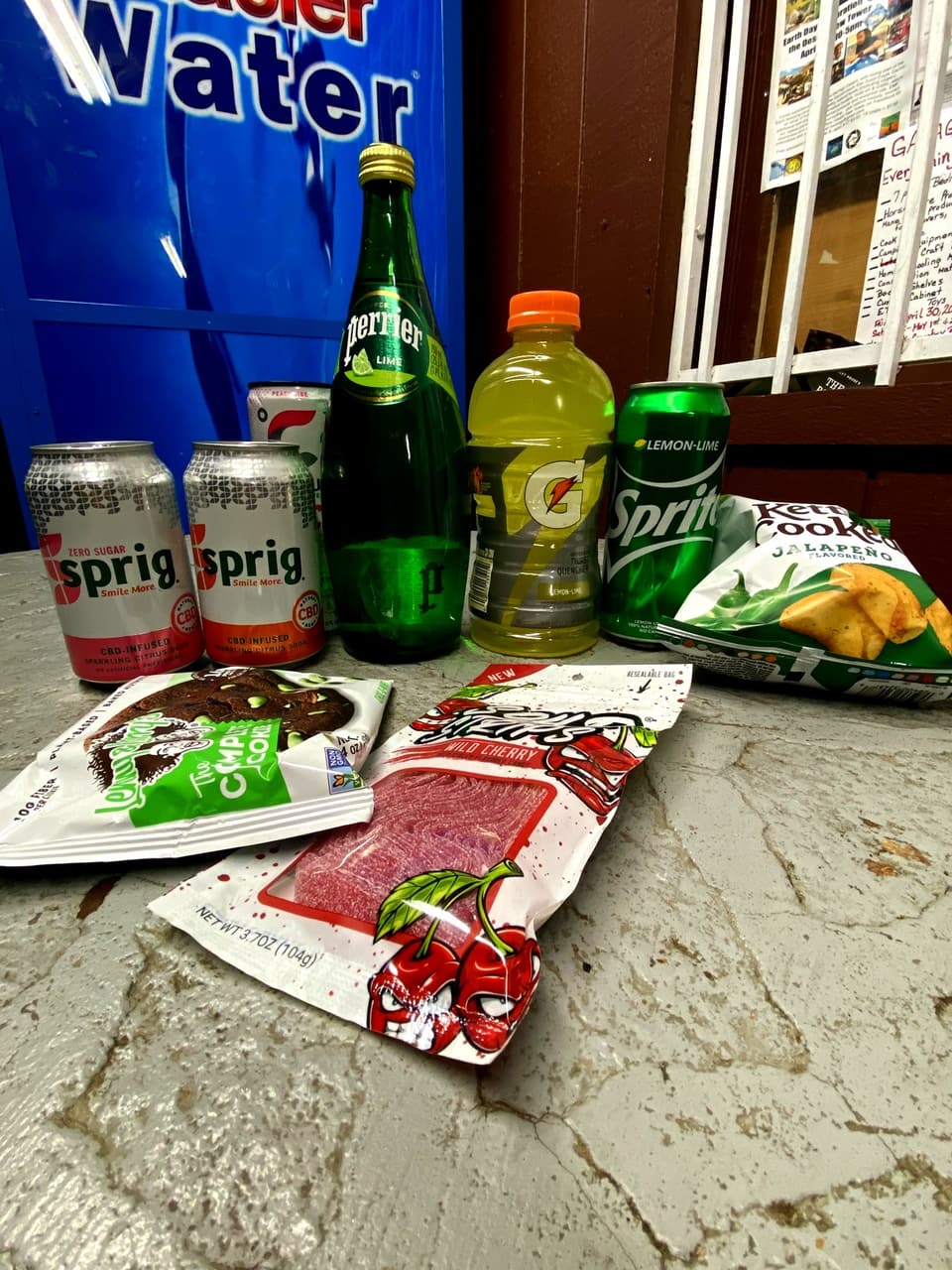 Sprig sodas, Perrier, Gatorade, Sprite, jalapeño chips, a Lenny &amp; Larry’s cookie and Sour Punch candy on a bench